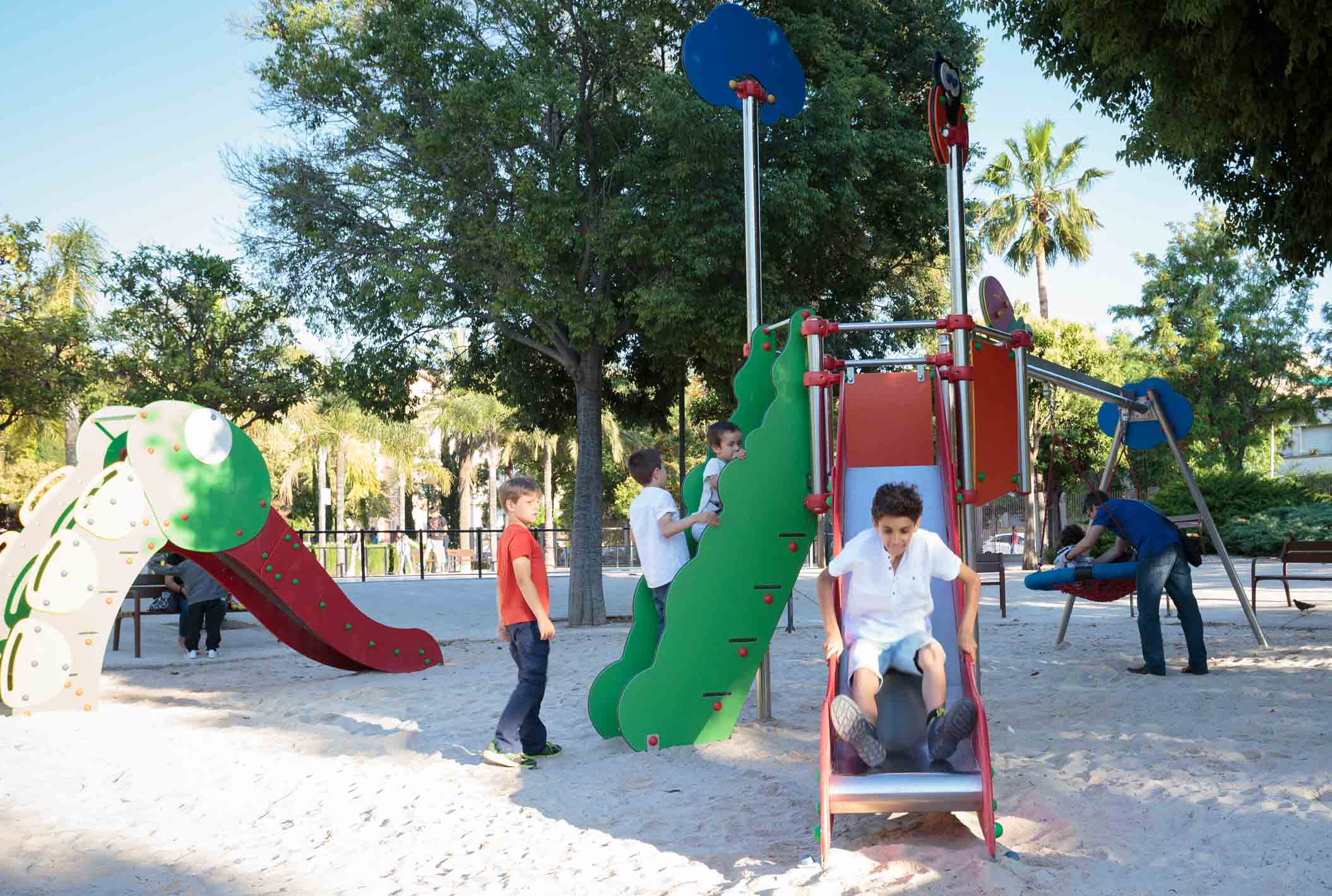 niños jugando en parque infantil con tobogán urbano